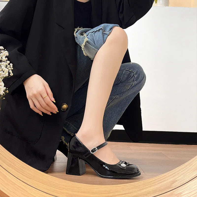 Women's black patent leather chunky heel shoes with round toe and buckle fastening.