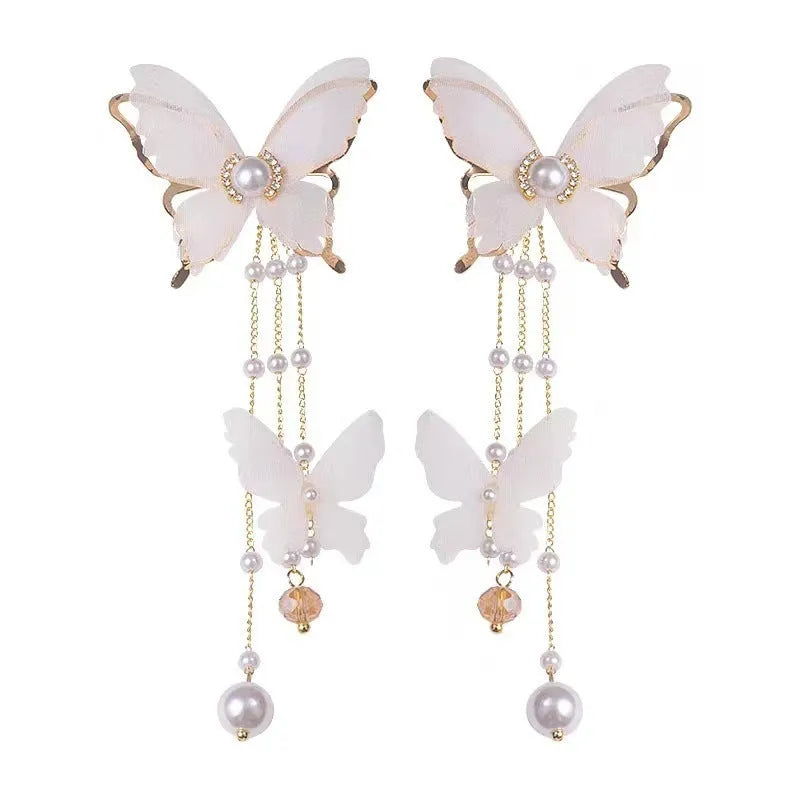 White butterfly-shaped drop earrings with pearls, rhinestones, and tassel lace details on a model.