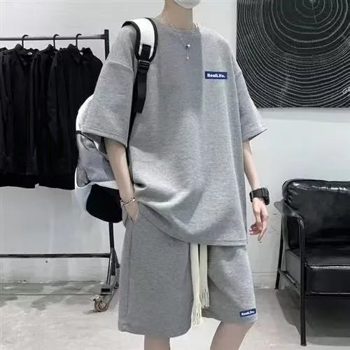 A man modelling a waffle-patterned grey short-sleeve top and matching shorts leisure set.