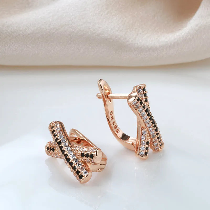 Pair of rose gold copper earrings with hollow-out X-shaped geometric design on light background