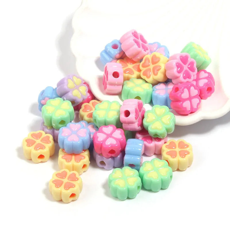 A selection of 15mm frosted acrylic beads showing a raised cartoon love and four-leaf clover pattern in various colours.