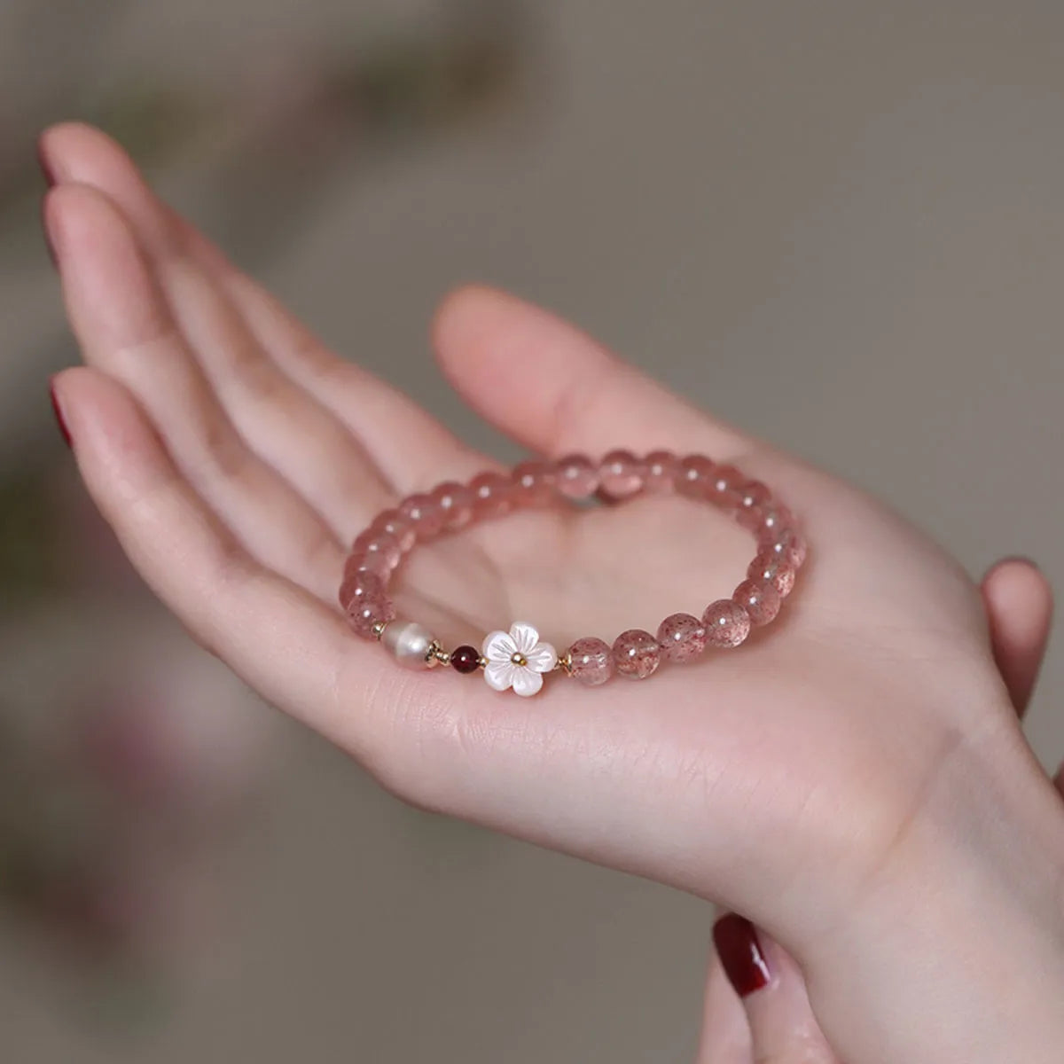Strawberry quartz peach blossom crystal bracelet with floral design on wrist