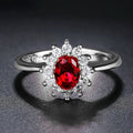 Women's copper floral ring with inlaid zirconium stones in green, blue, or red on a hand.