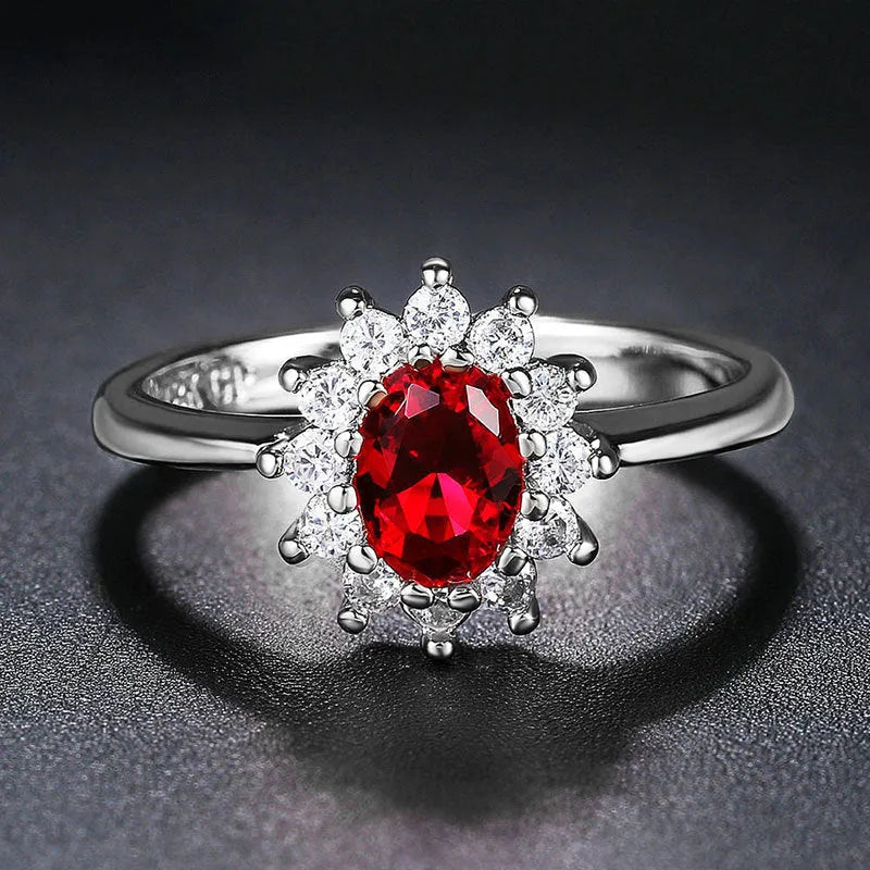 Women's copper floral ring with inlaid zirconium stones in green, blue, or red on a hand.