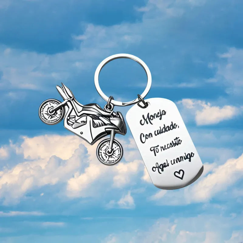 Silver motorcycle charm on a stainless steel key ring next to a red flannel storage bag.