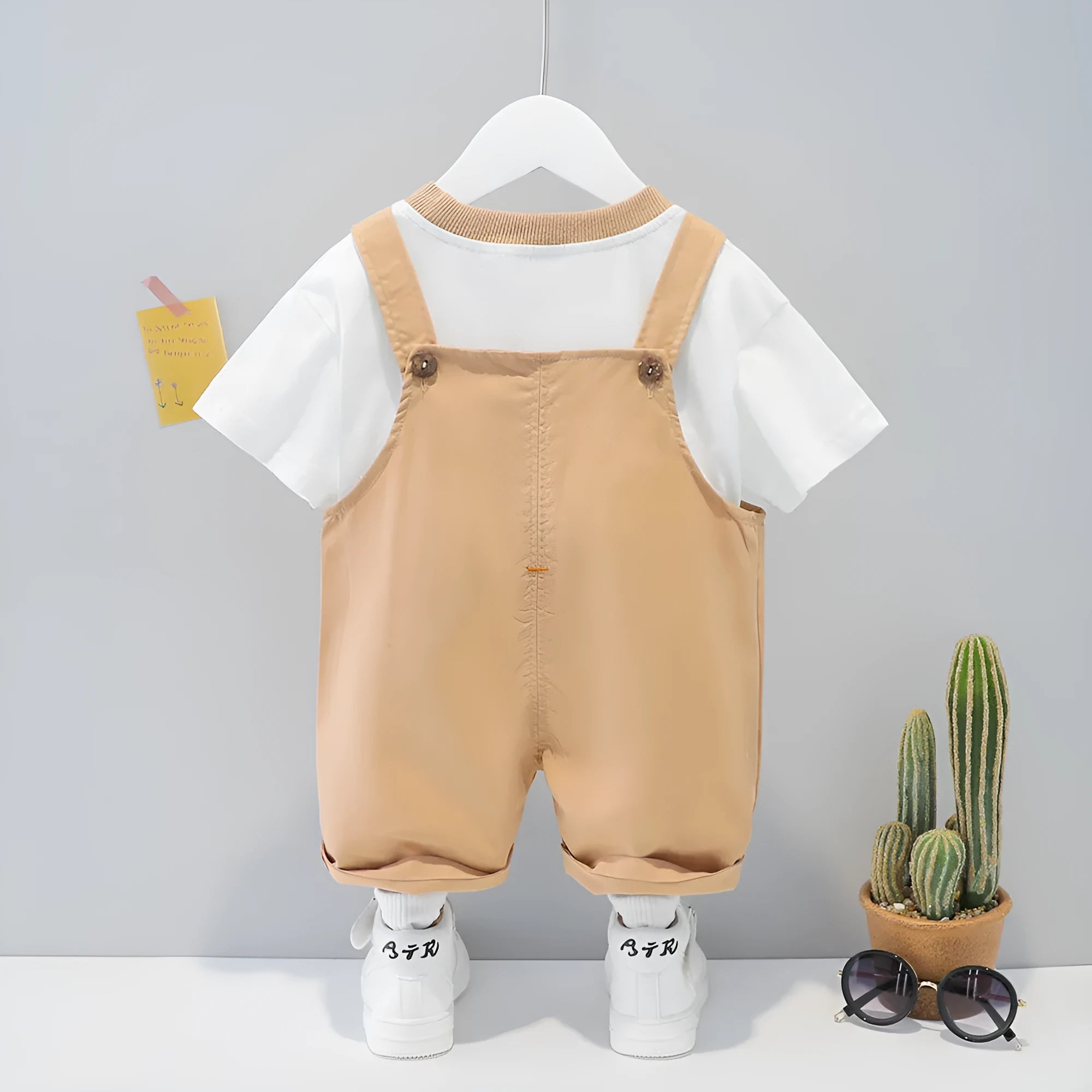 Yellow cotton baby cartoon short-sleeved overalls with strap design on a hanger
