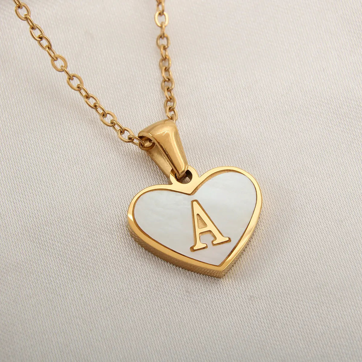 Gold plated heart-shaped necklace with a personalised initial letter and white shell detail on a 50cm adjustable chain.