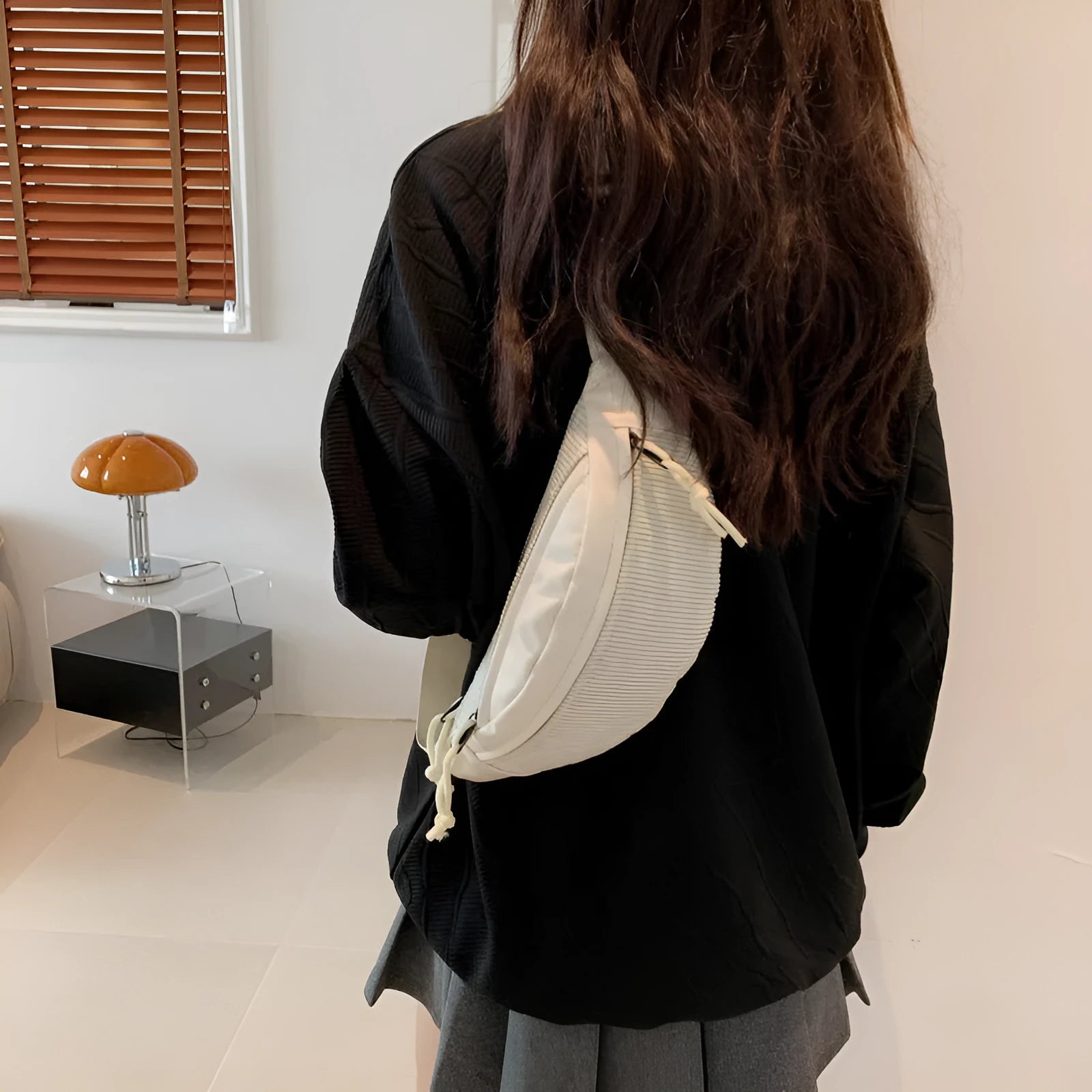 Corduroy crossbody bag in oval shape with brown colour, slit outer pocket, and crossbody strap for daily use