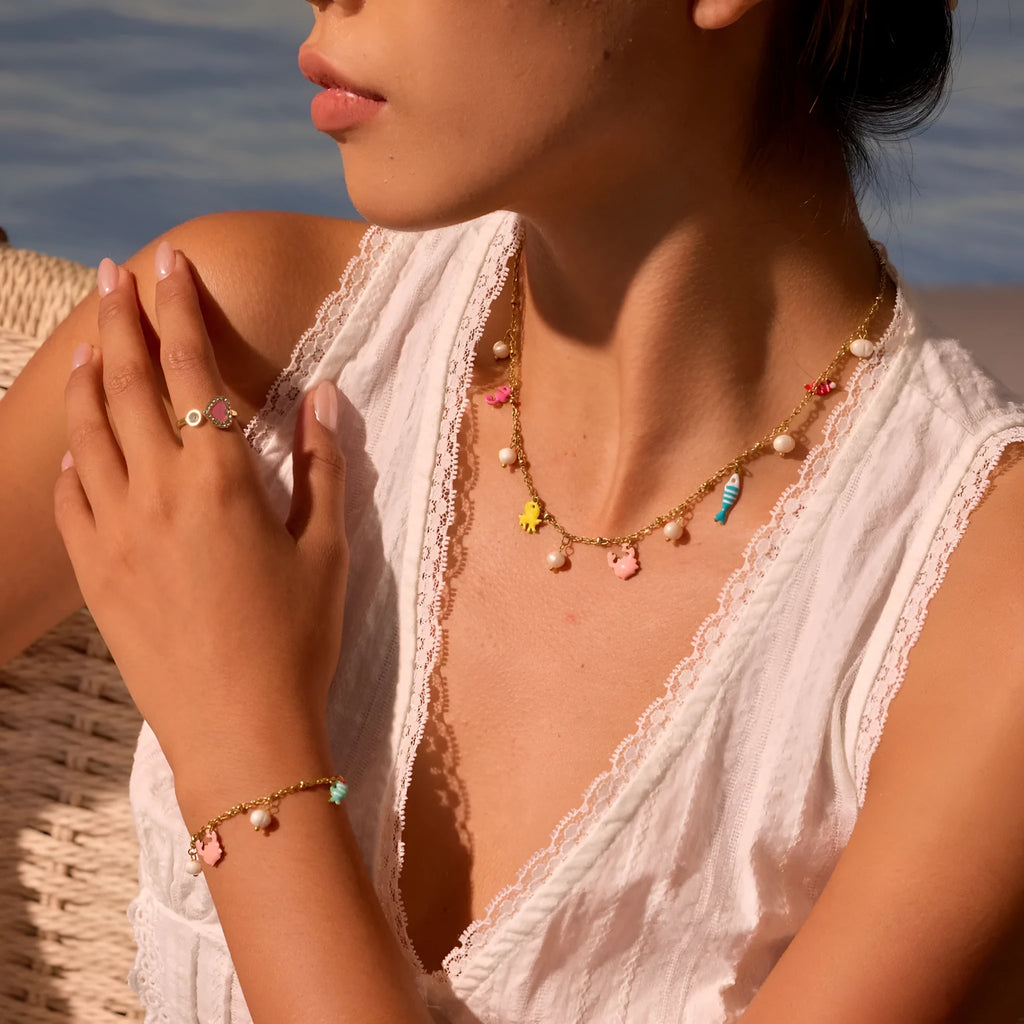 Stainless steel geometric pendant necklace with 18K electroplate and matching alloy bracelet on surface