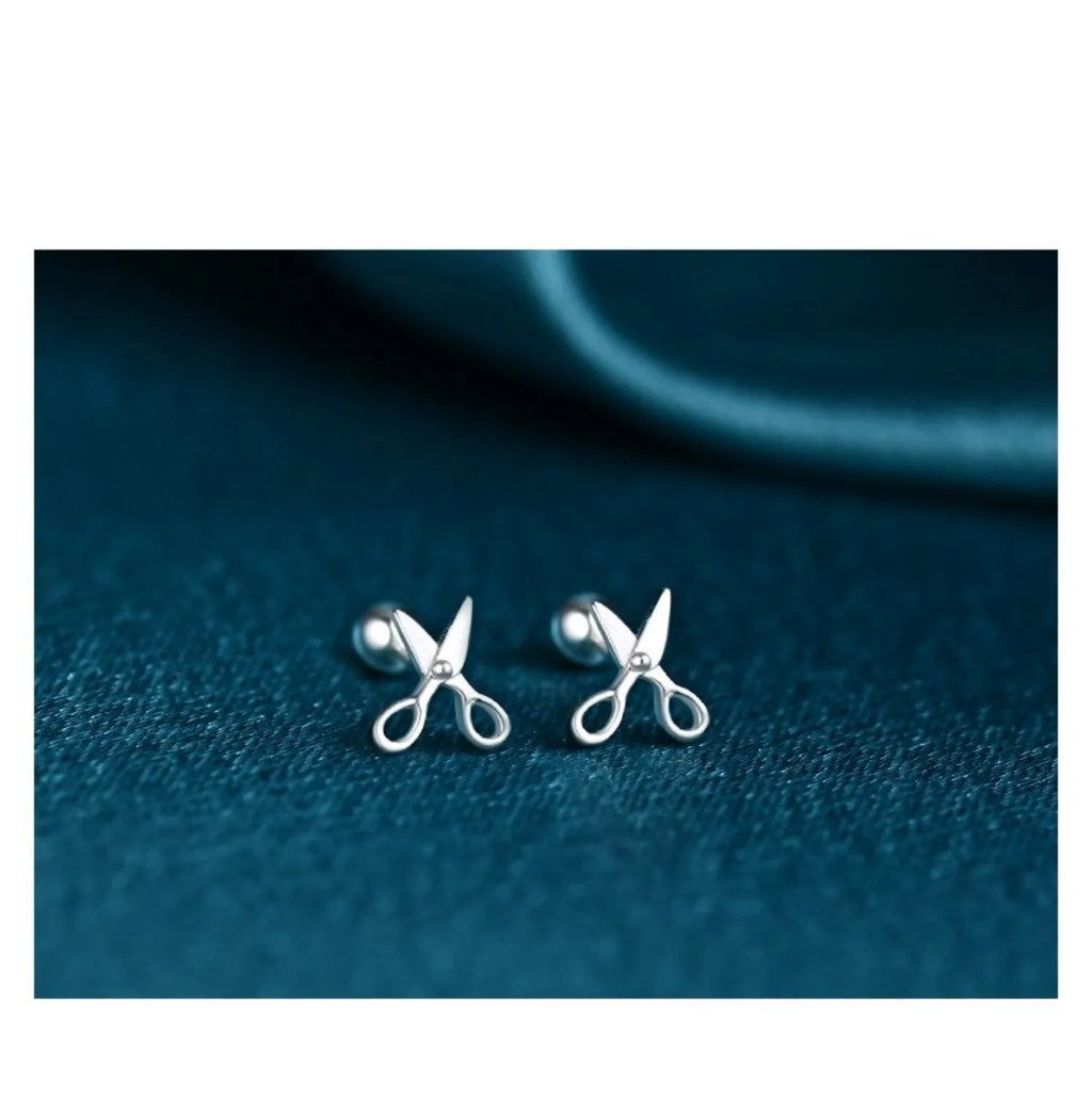 A pair of pure silver ear studs with a miniature scissors design on the screw-back fastener.