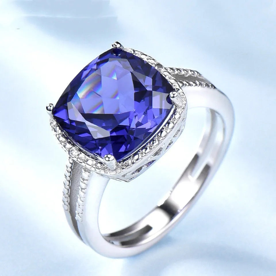 Women's 925 Sterling Silver ring with a blue Tanzanite stone, shown on a finger.