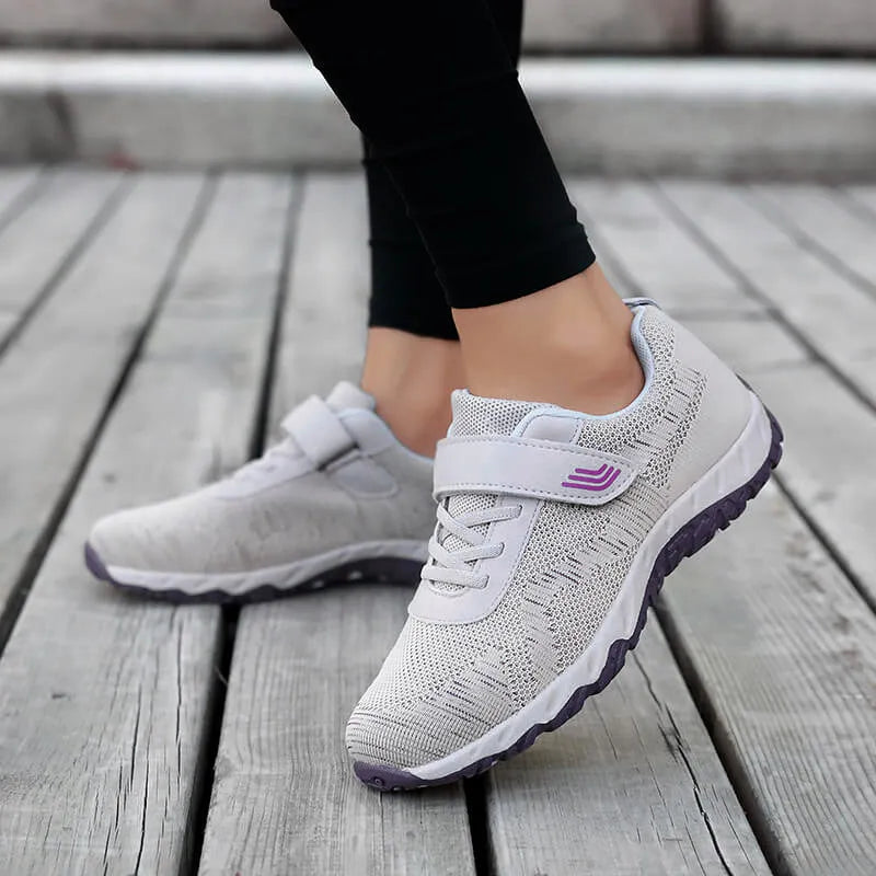 Women's grey purple wedge shoe with Velcro strap and mesh upper on a solid colour background.