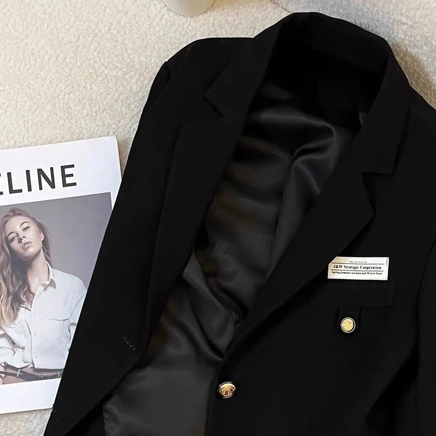 Women's black loose-fit short suit coat with regular sleeves and pockets on a hanger.