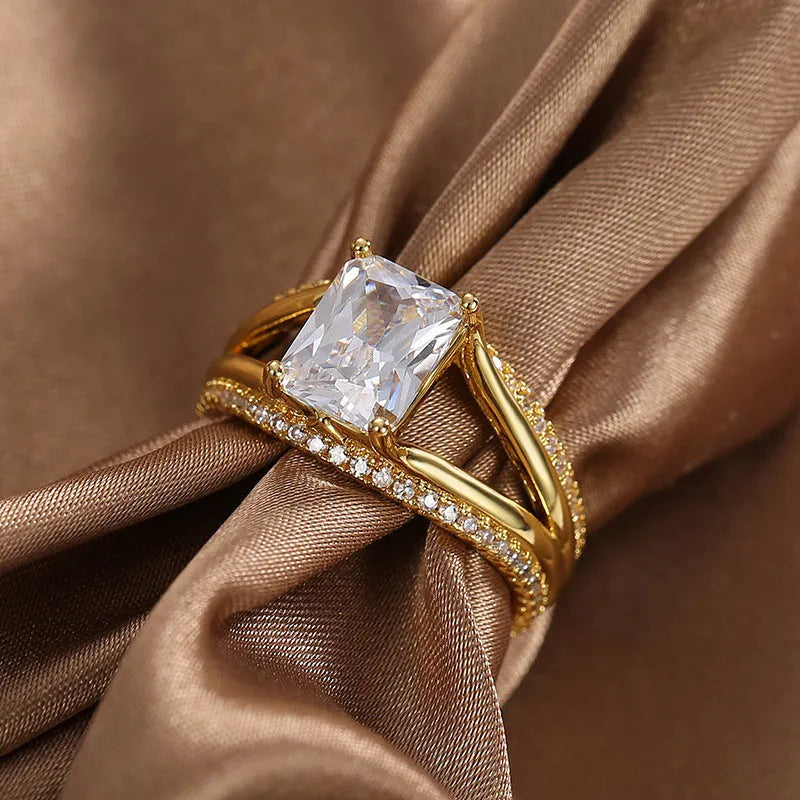 Gold-colour geometric women's ring with a square zircon centre, shown on a finger.