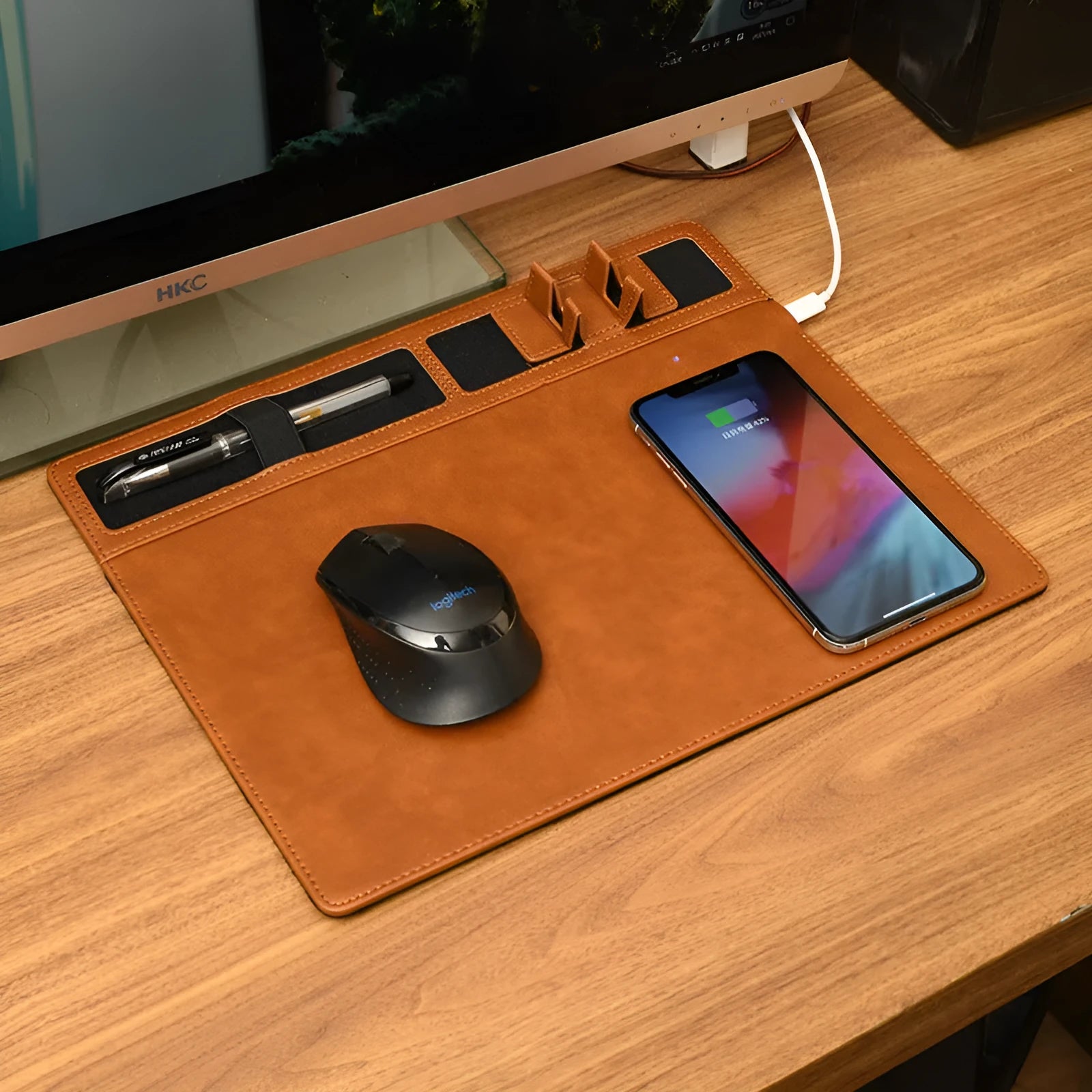 Pink wireless charging mouse pad with integrated mobile phone holder on a desk.