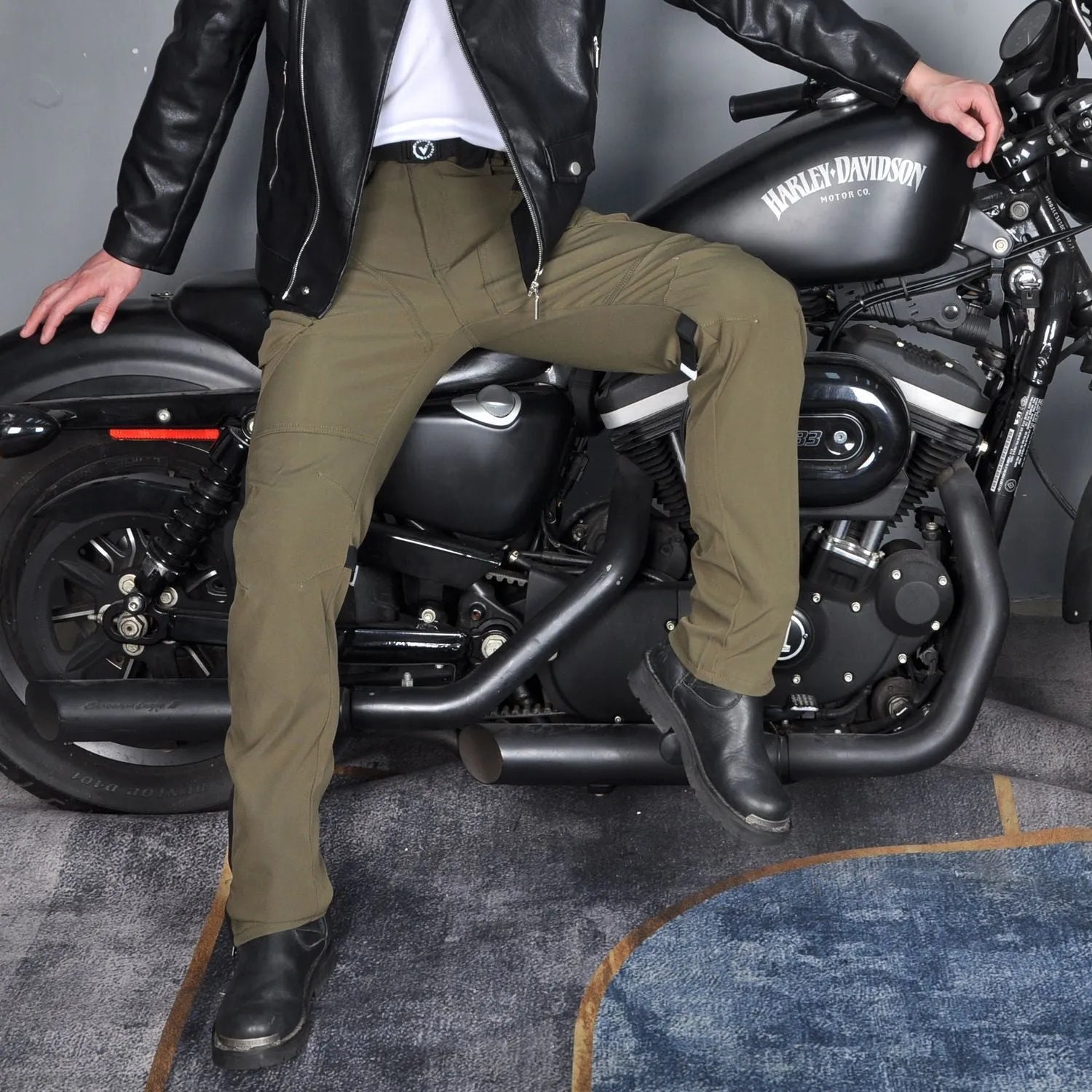 Men's green waterproof motorcycle trousers with belt and protective knee pads laid out flat.
