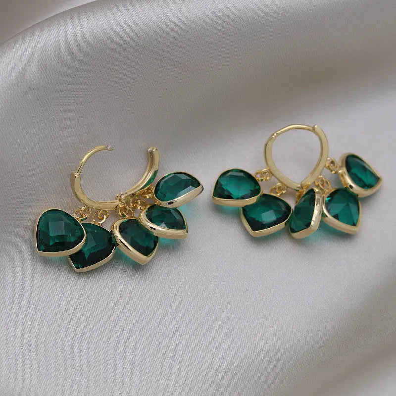 Green glass heart-shaped pendant on copper ear clip earrings with alloy inlay detail.