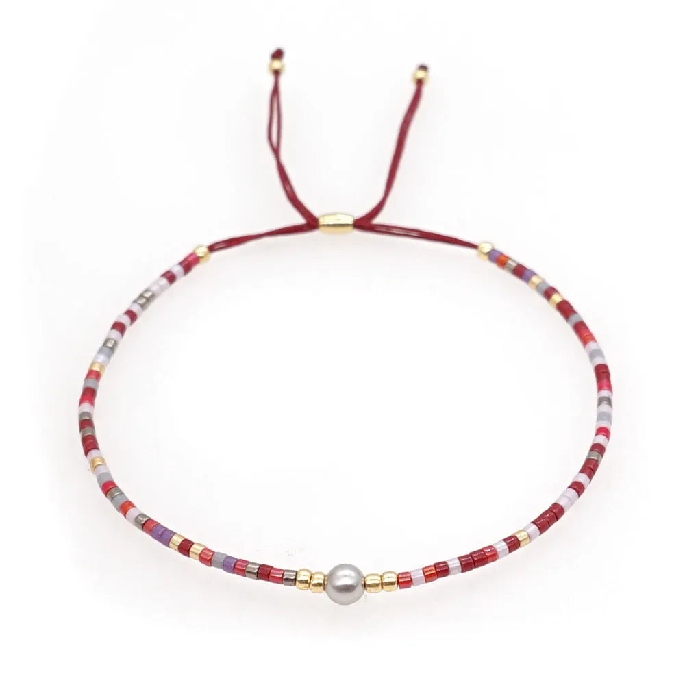 Close-up of a handmade Bohemian women's bracelet with colourful semi-precious stone and glass beads on a geometric string.
