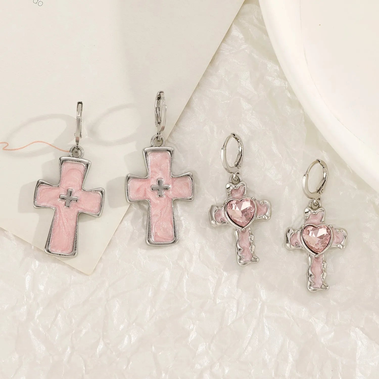 Women's alloy crystal earrings showing five colour options: white cross, white peach heart, white cross, black cat, and antique silver star design.