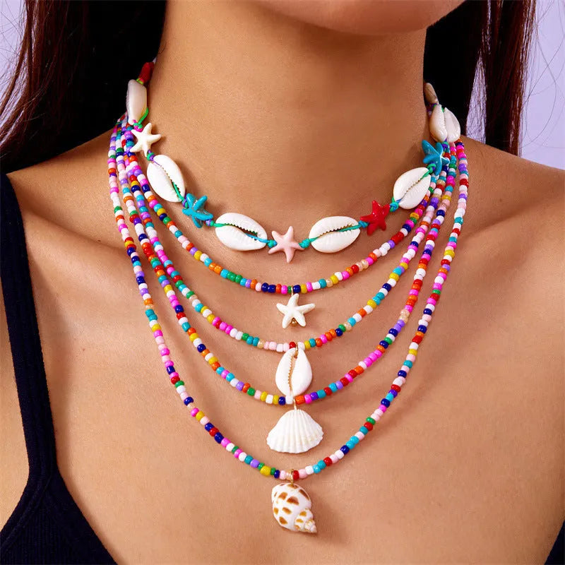 Blue multi-layer women's necklace set with starfish, shell, and conch bead pendants on bead chains