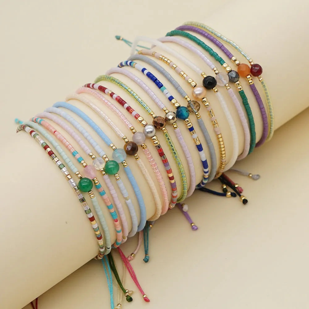 Close-up of a handmade Bohemian women's bracelet with colourful semi-precious stone and glass beads on a geometric string.