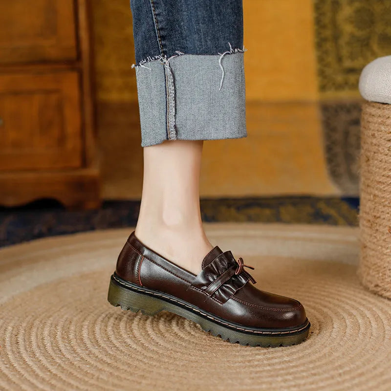 Women's black leather shoes with round toe and flat chunky heel on a neutral background