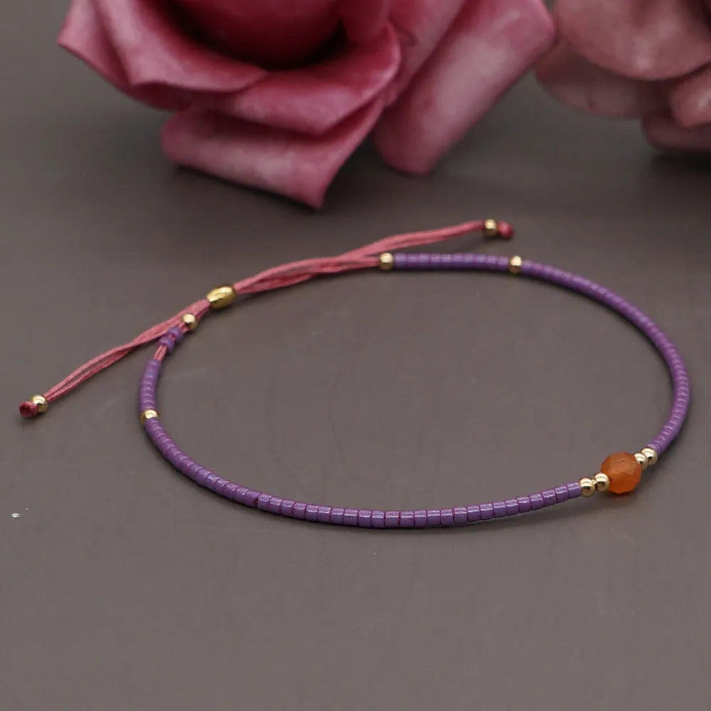 Close-up of a handmade Bohemian women's bracelet with colourful semi-precious stone and glass beads on a geometric string.