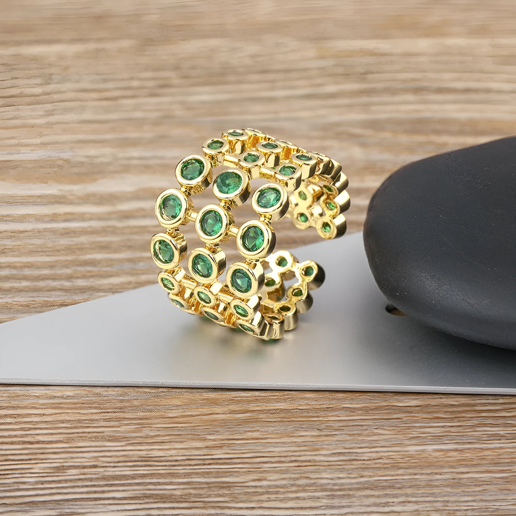 Wide band ring with gold plating and exaggerated green zircon detailing on copper base