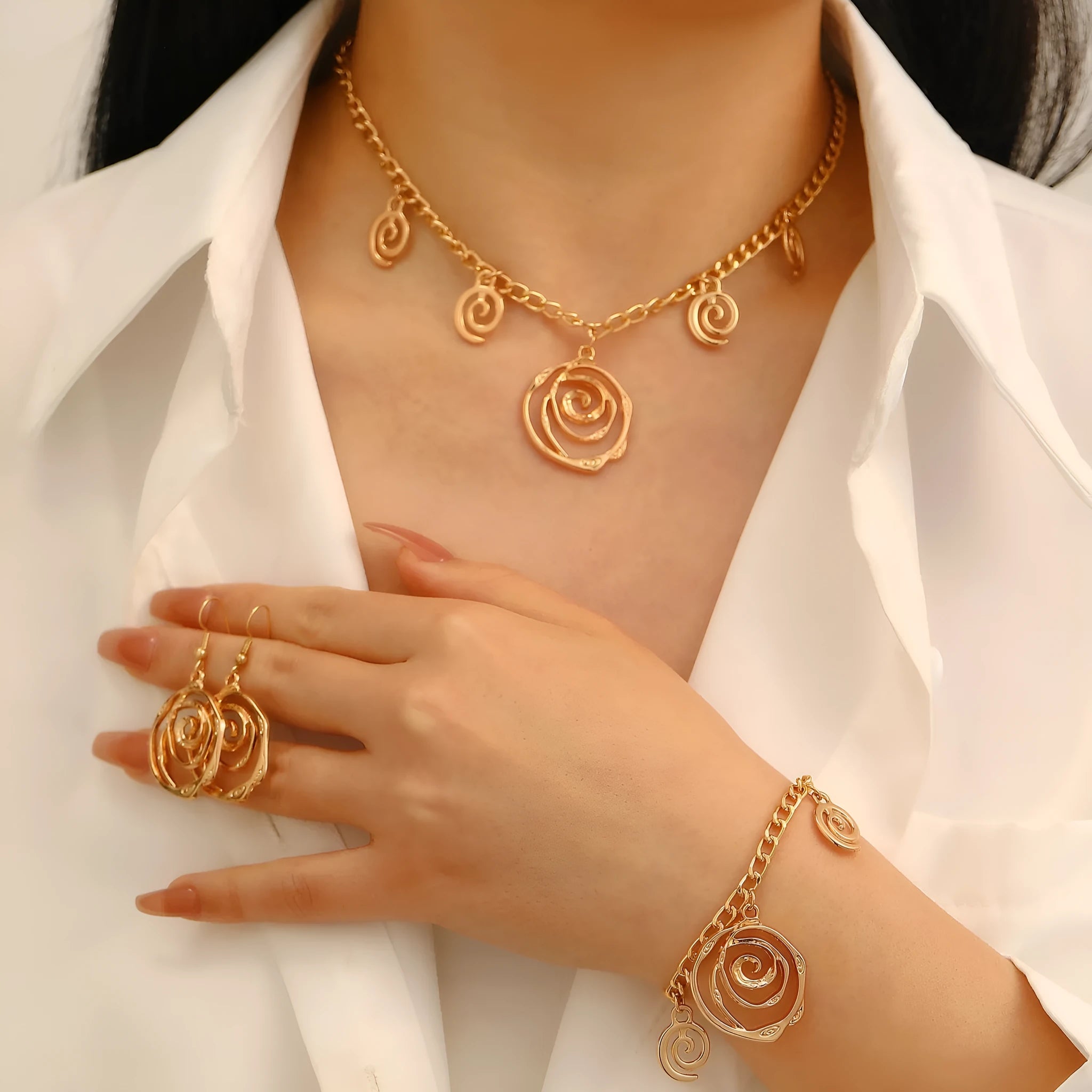 Women's spiral donut charm jewellery set with gold necklace, bracelet and earrings on white background