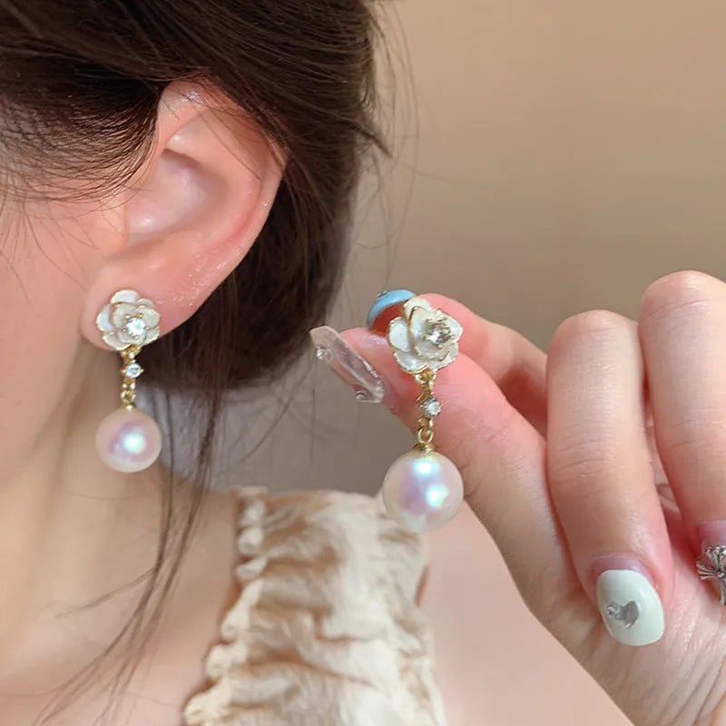 Close-up of women's camellia pearl flower stud earrings in alloy with butterfly clasp