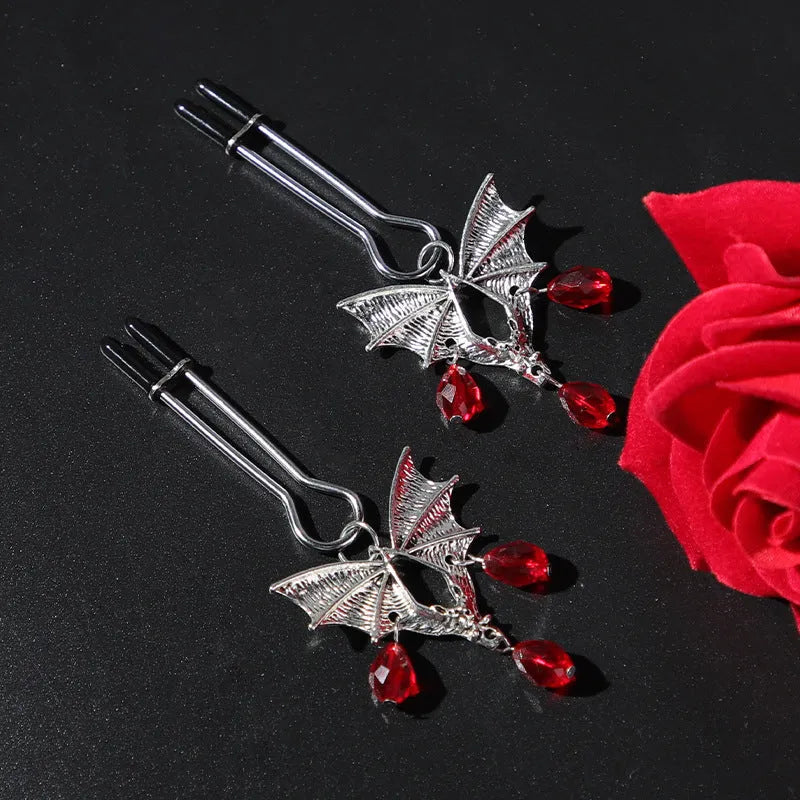 Silver bat-shaped nipple clamp with ruby accent detail and adjustable pressure mechanism