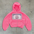 A person wearing a black unisex loose-fit hooded zip-up jacket with a letter pattern and zippered pockets.