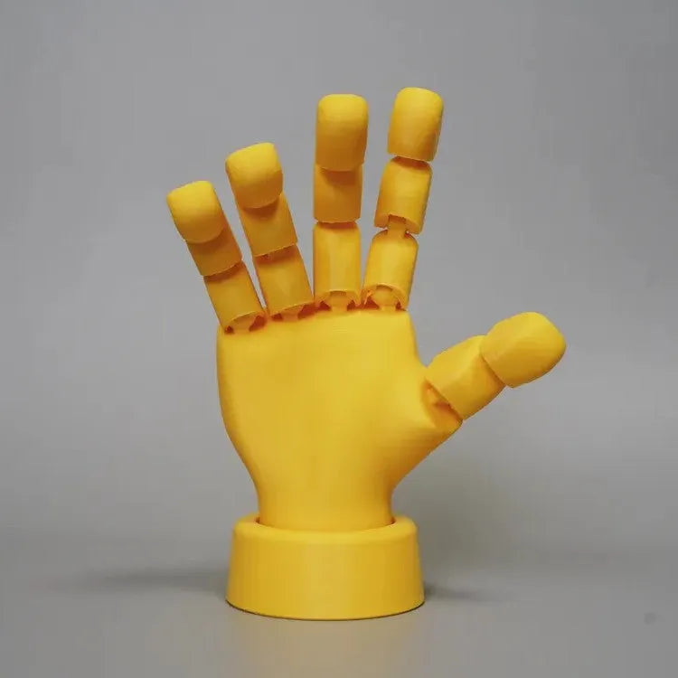 Yellow articulated hand prop with movable joints on a white background.