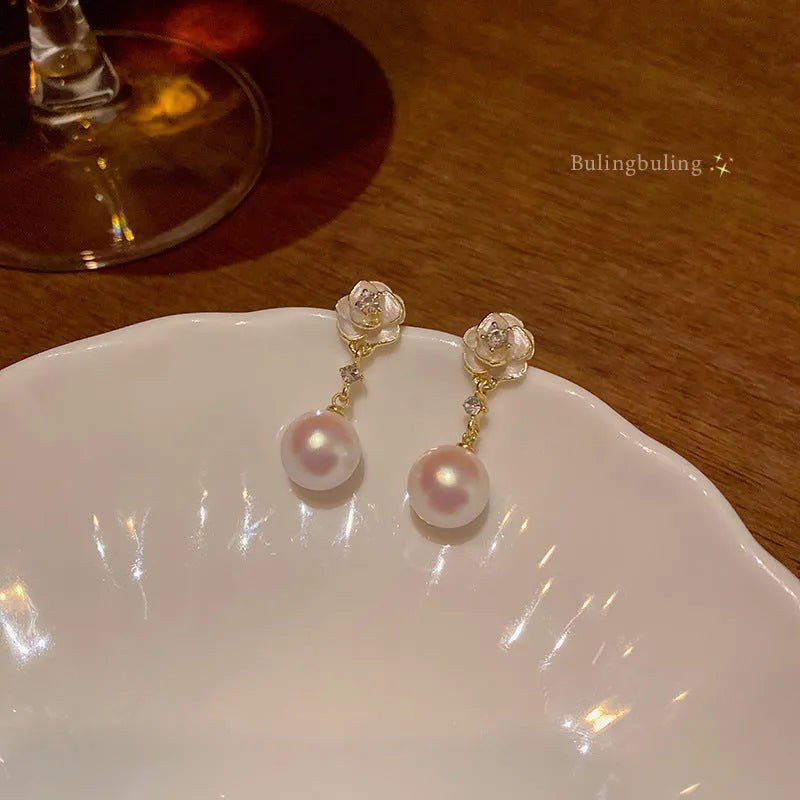 Close-up of women's camellia pearl flower stud earrings in alloy with butterfly clasp
