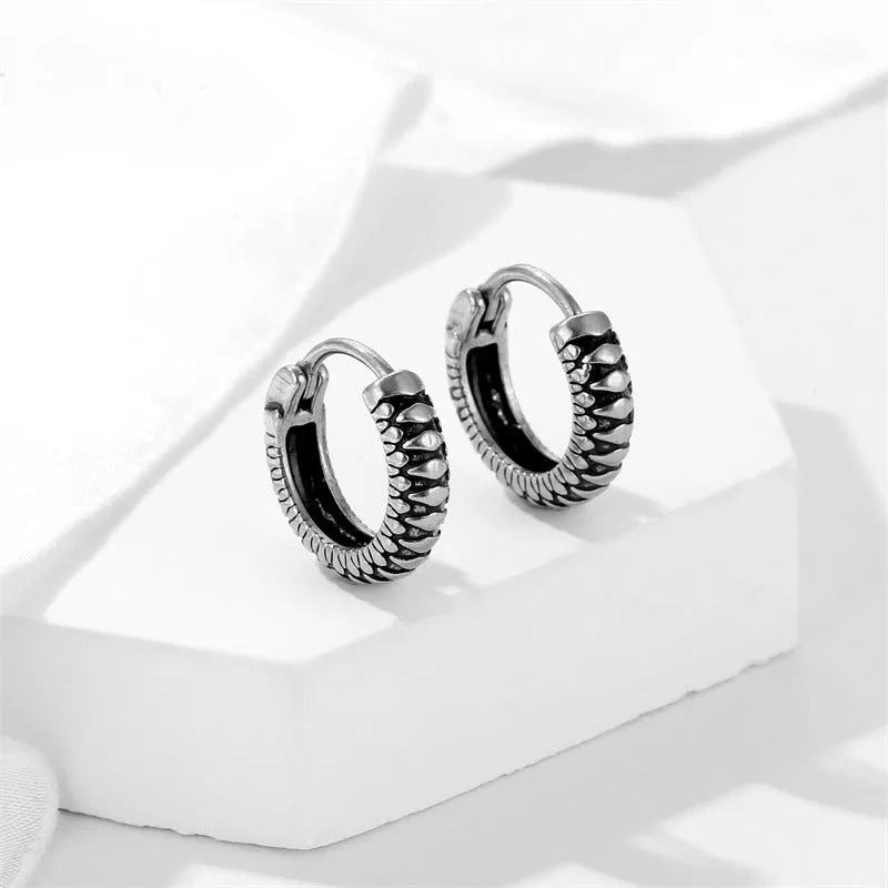 Silver geometric circular earrings made from twisted stainless steel stripes on a white background.