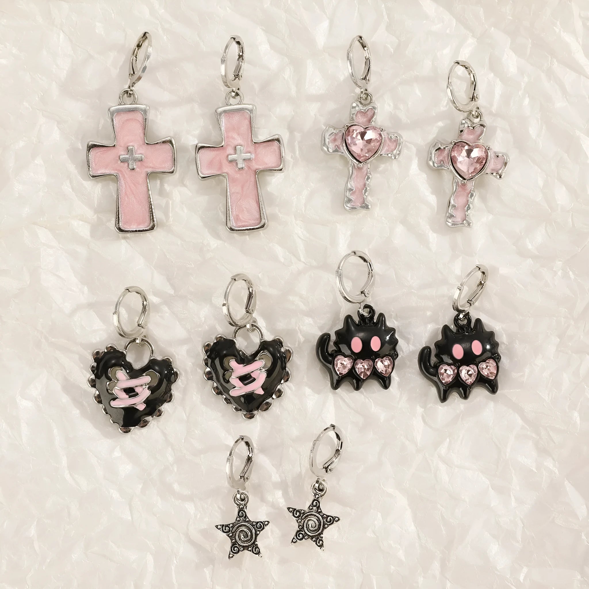 Women's alloy crystal earrings showing five colour options: white cross, white peach heart, white cross, black cat, and antique silver star design.