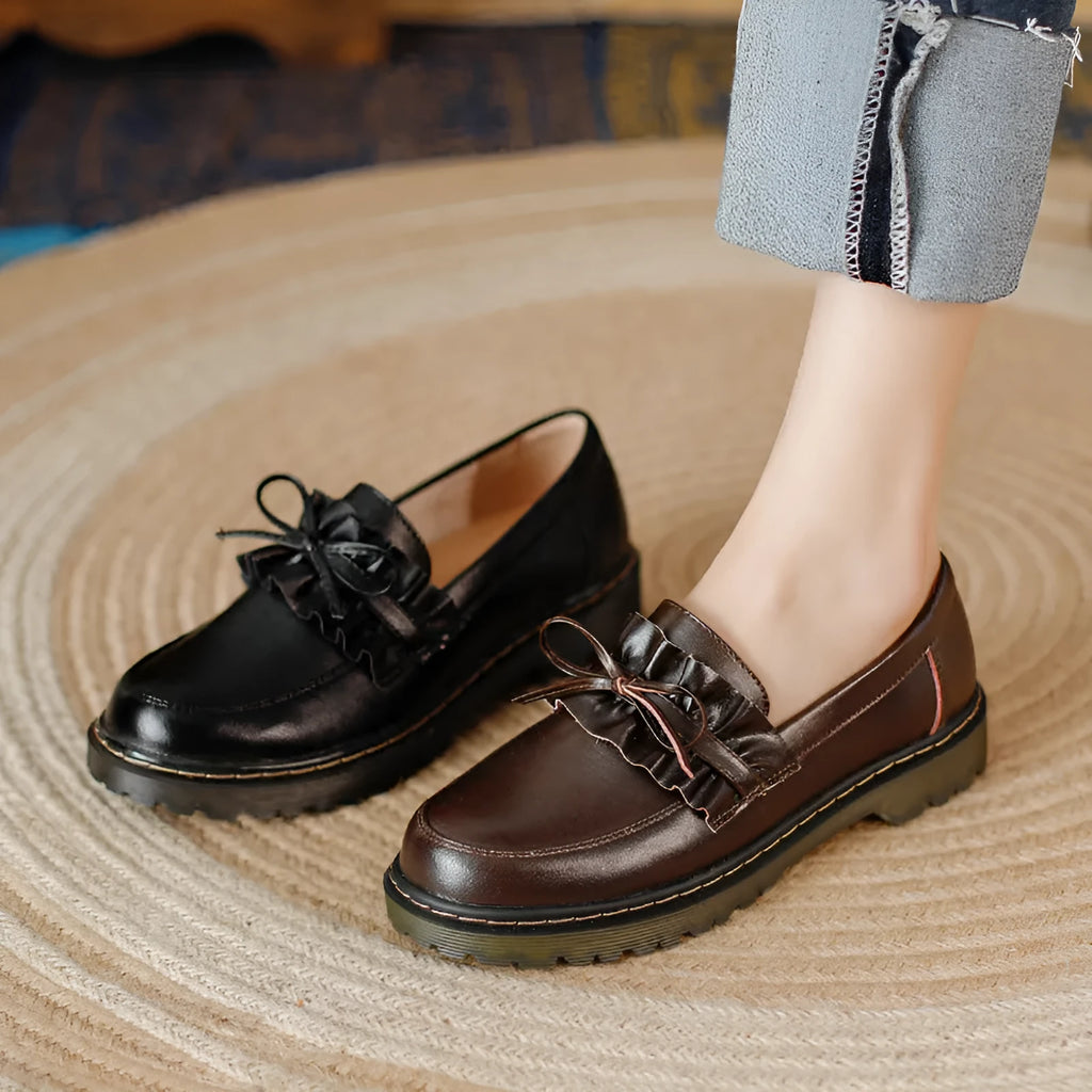 Women's black leather shoes with round toe and flat chunky heel on a neutral background