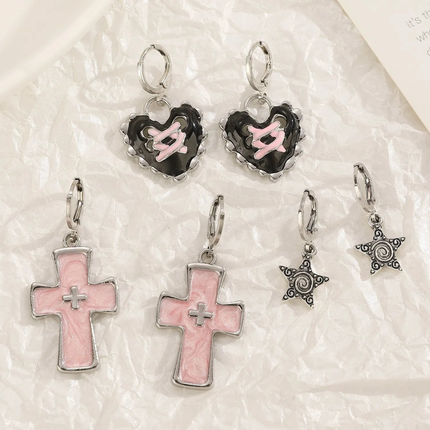 Women's alloy crystal earrings showing five colour options: white cross, white peach heart, white cross, black cat, and antique silver star design.
