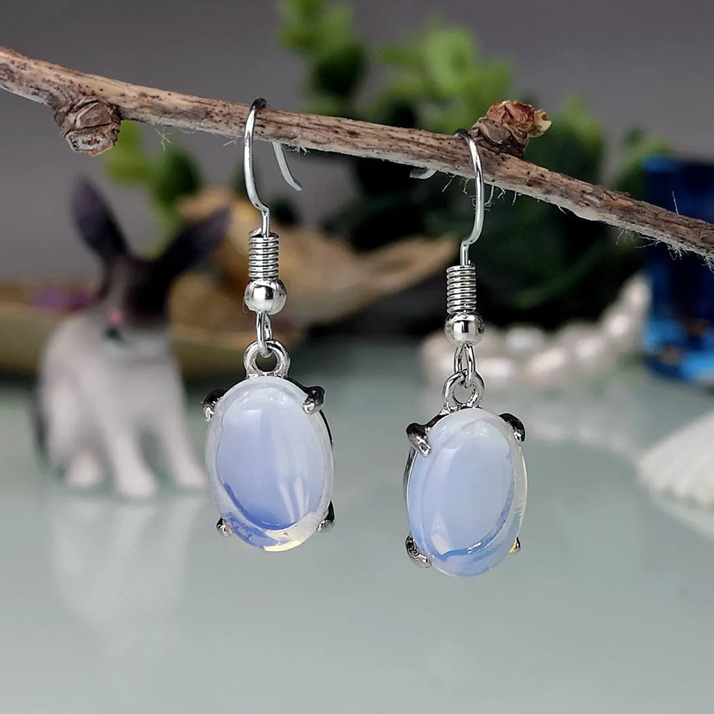 Pair of white retro-style drop earrings with a cross design and opal-like finish.