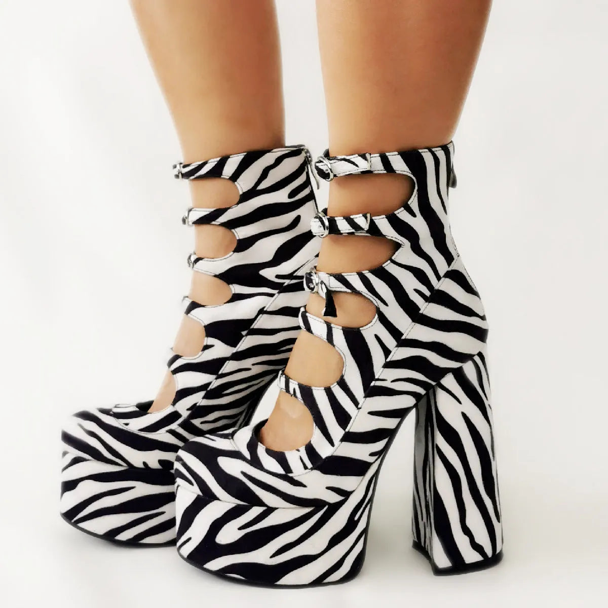 Women's black patent leather platform ankle boots with a thick heel and serpentine buckle fastening.