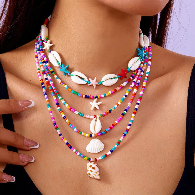 Blue multi-layer women's necklace set with starfish, shell, and conch bead pendants on bead chains