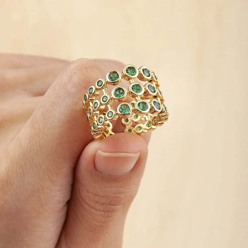 Wide band ring with gold plating and exaggerated green zircon detailing on copper base