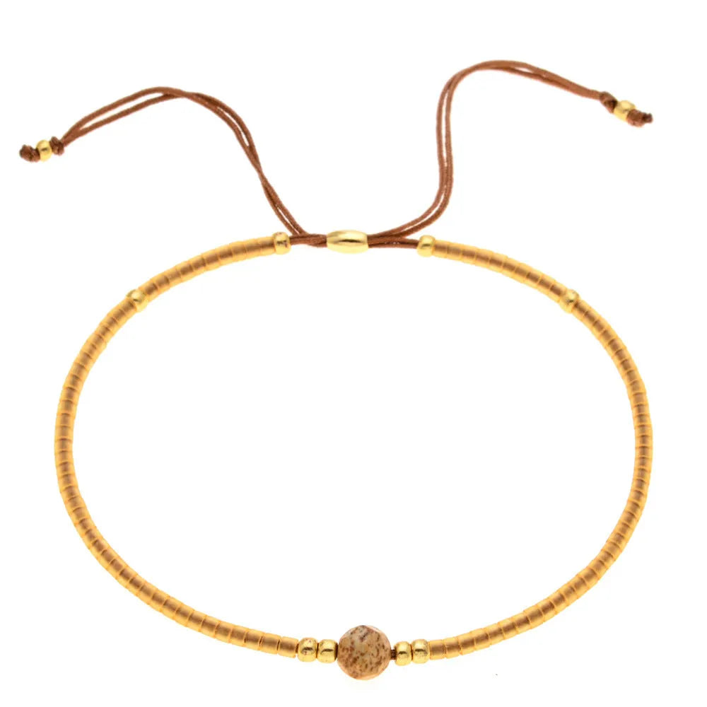 Close-up of a handmade Bohemian women's bracelet with colourful semi-precious stone and glass beads on a geometric string.