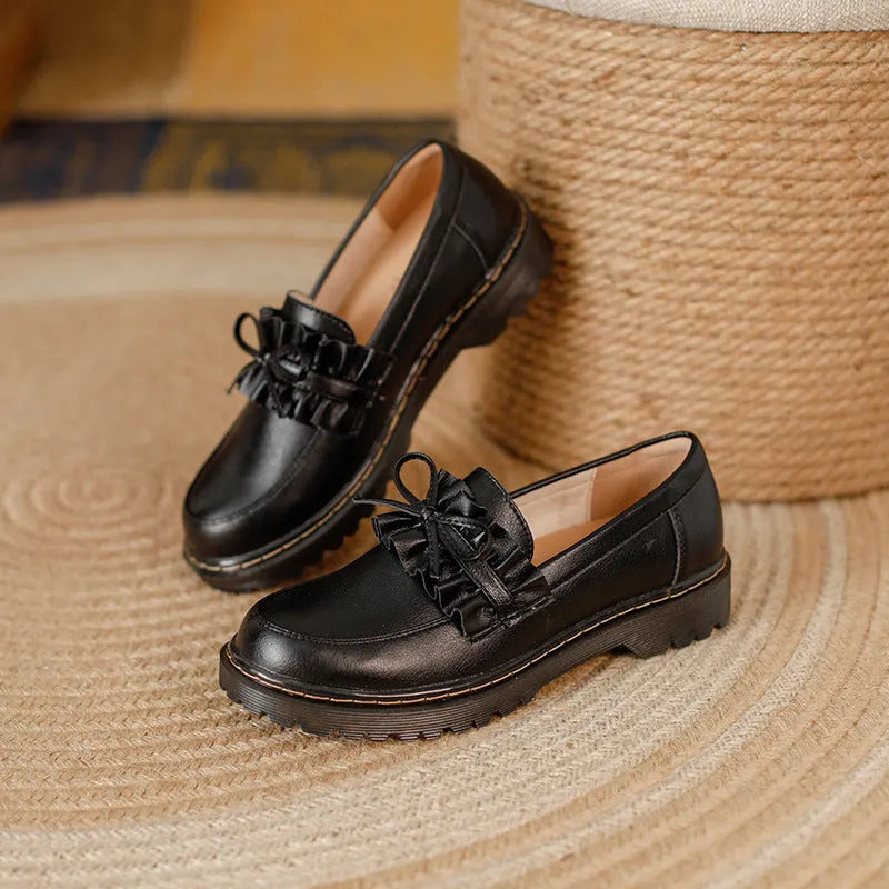 Women's black leather shoes with round toe and flat chunky heel on a neutral background