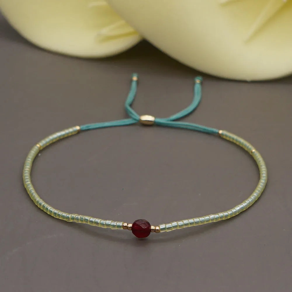 Close-up of a handmade Bohemian women's bracelet with colourful semi-precious stone and glass beads on a geometric string.