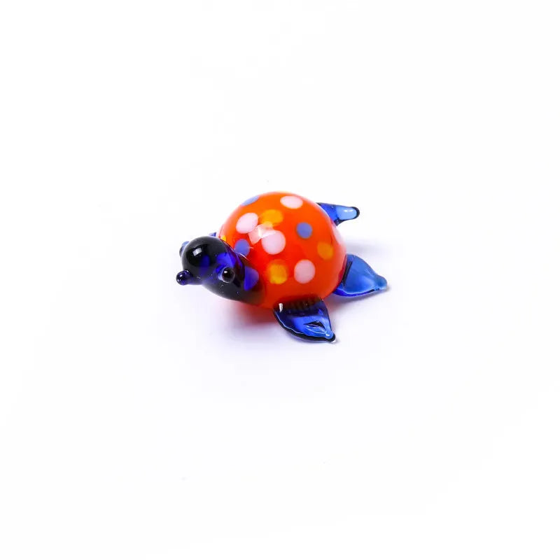 Geometric glass turtle ornament with blue head and blue shell on wooden surface