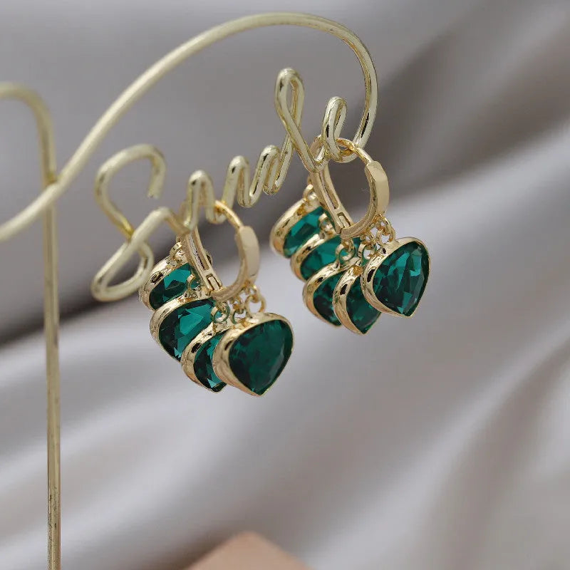 Green glass heart-shaped pendant on copper ear clip earrings with alloy inlay detail.
