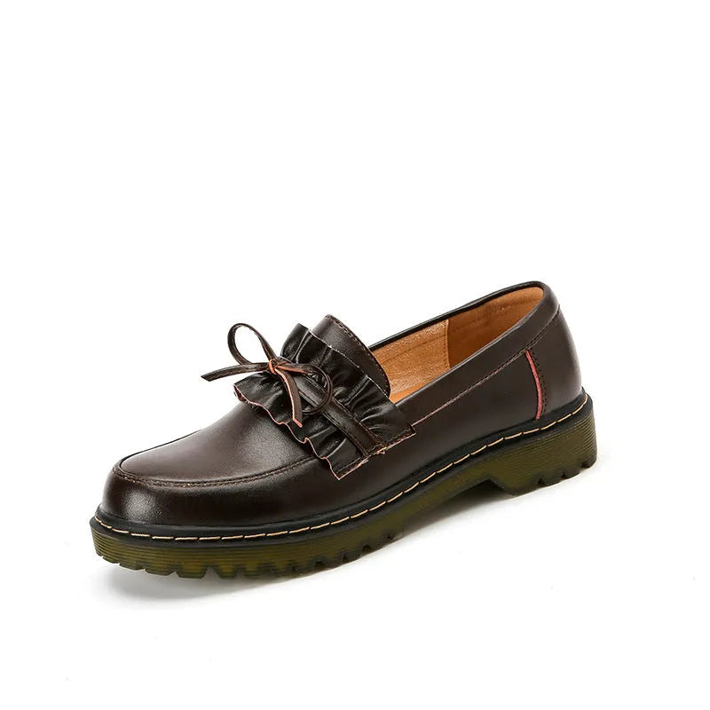 Women's black leather shoes with round toe and flat chunky heel on a neutral background