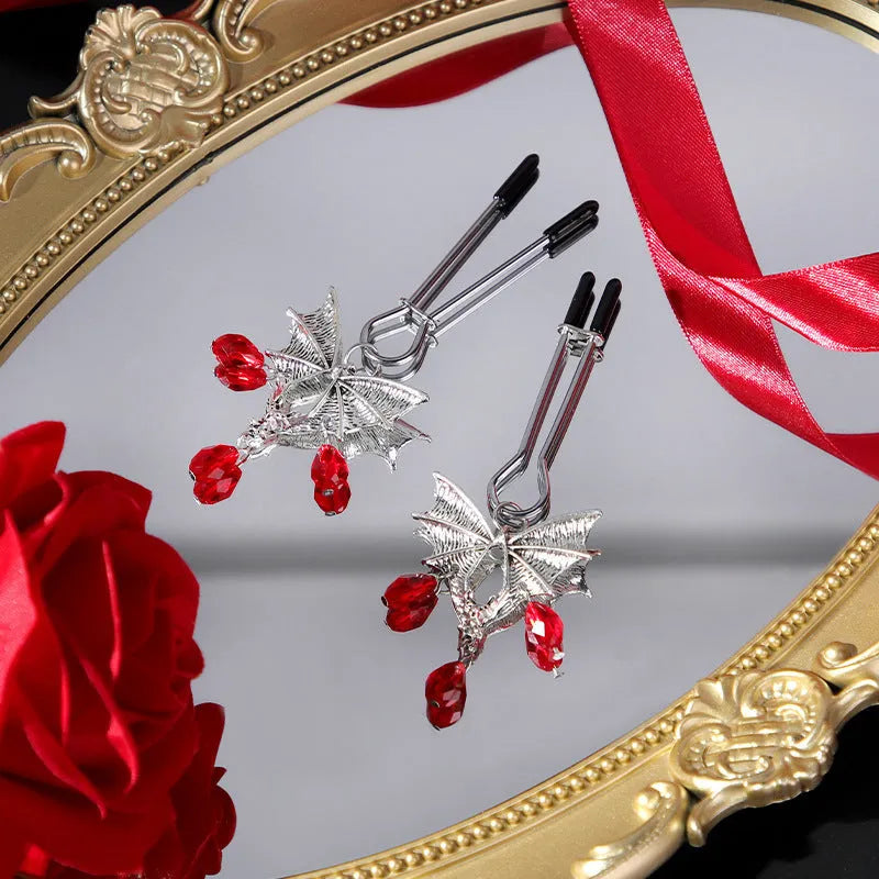 Silver bat-shaped nipple clamp with ruby accent detail and adjustable pressure mechanism