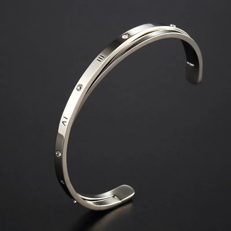 Open-ended stainless steel bracelet with zircon stones in gold, rose, or silver colour on a wrist.